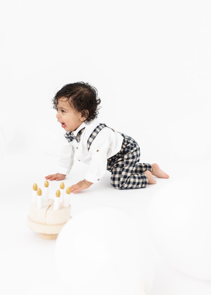 Baby crawling on a white background as part of a cakesmash photoshoot by lauren vanier photography